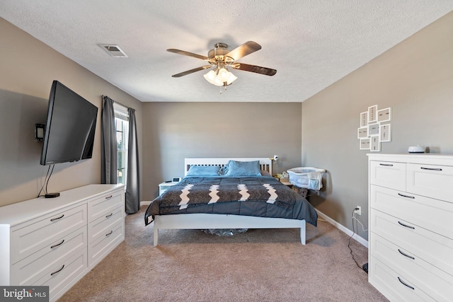 carpeted bedroom with ceiling fan and a textured ceiling