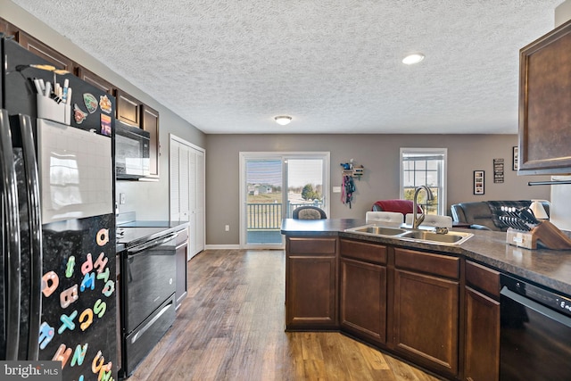 kitchen with black appliances, sink, dark brown cabinets, a textured ceiling, and dark hardwood / wood-style floors