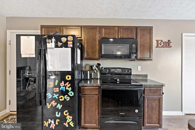 kitchen with dark wood-type flooring, black appliances, and a textured ceiling