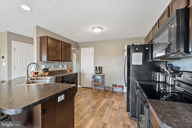 kitchen featuring sink, a textured ceiling, dark hardwood / wood-style flooring, black appliances, and dark brown cabinets