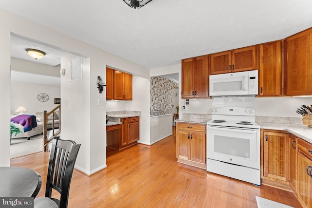 kitchen with white appliances, baseboards, light wood finished floors, and brown cabinetry