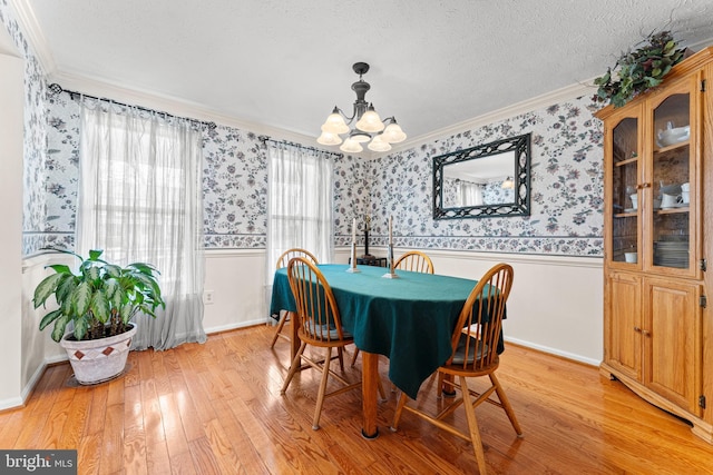 dining room with wallpapered walls, light wood finished floors, and wainscoting