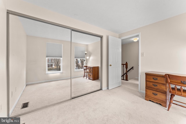 carpeted bedroom with a closet, visible vents, and baseboards