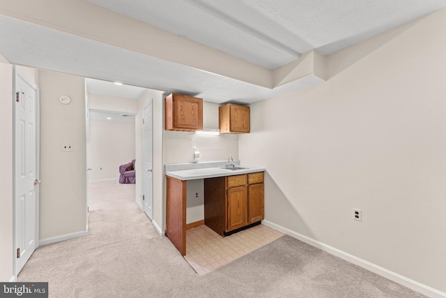 kitchen with light countertops, light colored carpet, brown cabinets, and baseboards