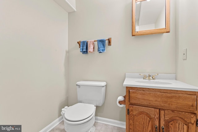 bathroom with toilet, tile patterned flooring, vanity, and baseboards