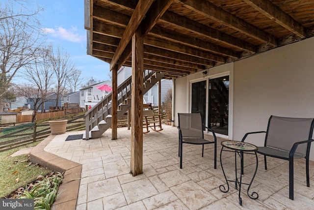 view of patio with stairs, fence, and a residential view