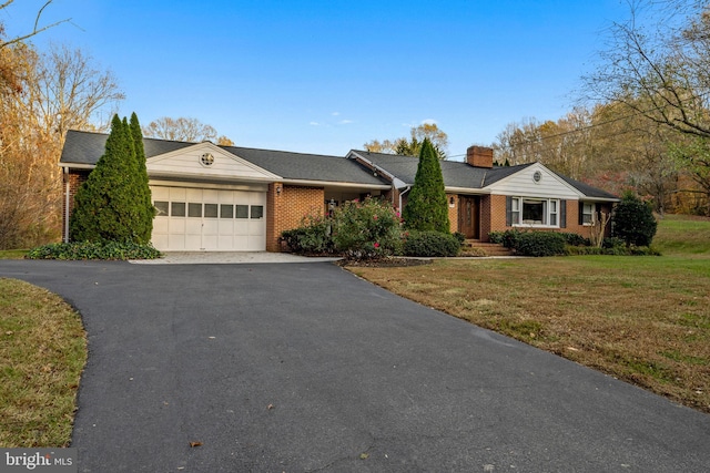 single story home featuring aphalt driveway, a garage, brick siding, a chimney, and a front yard