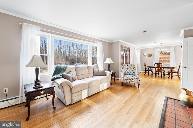 living room with light wood-type flooring, ornamental molding, a chandelier, and a wealth of natural light