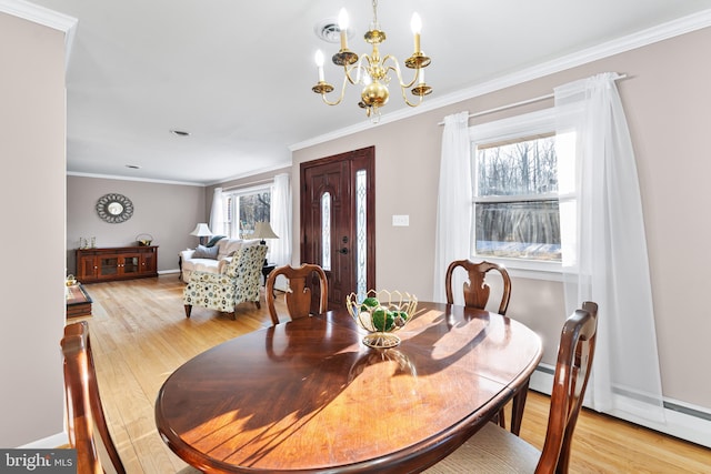 dining space featuring light wood finished floors, plenty of natural light, and ornamental molding