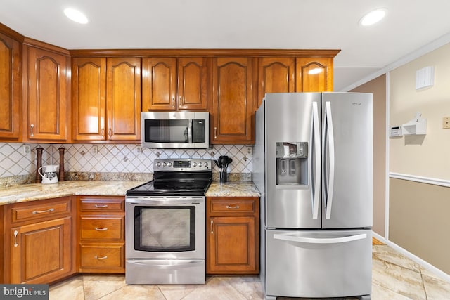 kitchen featuring stainless steel appliances, brown cabinets, crown molding, and light stone counters