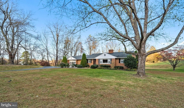 single story home with aphalt driveway, a garage, brick siding, a chimney, and a front yard