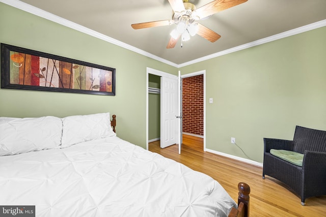 bedroom with ceiling fan, wood finished floors, baseboards, a closet, and crown molding