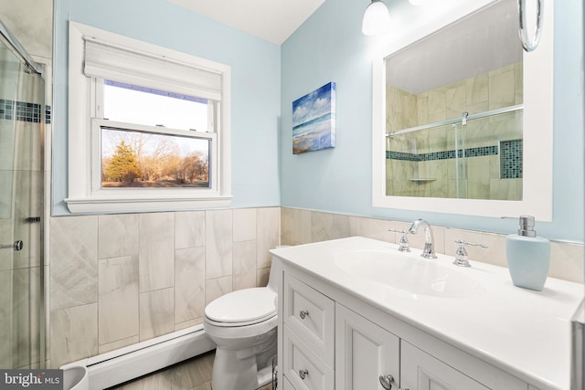 bathroom featuring tile walls, a baseboard radiator, toilet, vanity, and tiled shower