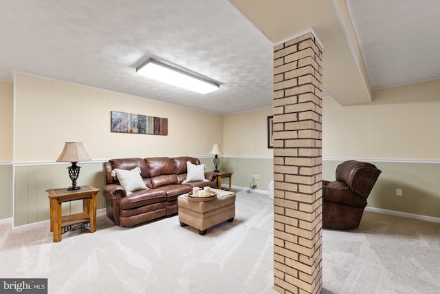 living area with light carpet, decorative columns, and a textured ceiling