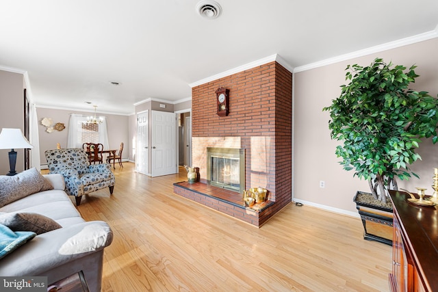 living room featuring visible vents, baseboards, light wood-type flooring, a brick fireplace, and crown molding