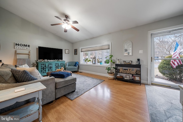 living room with light wood-type flooring, baseboards, vaulted ceiling, and a ceiling fan