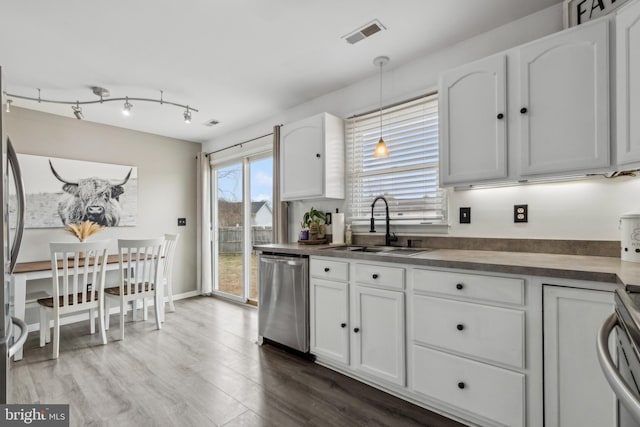 kitchen featuring hanging light fixtures, stainless steel dishwasher, dark countertops, and white cabinets