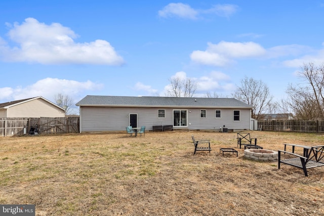 rear view of property featuring a fenced backyard, a yard, and a fire pit