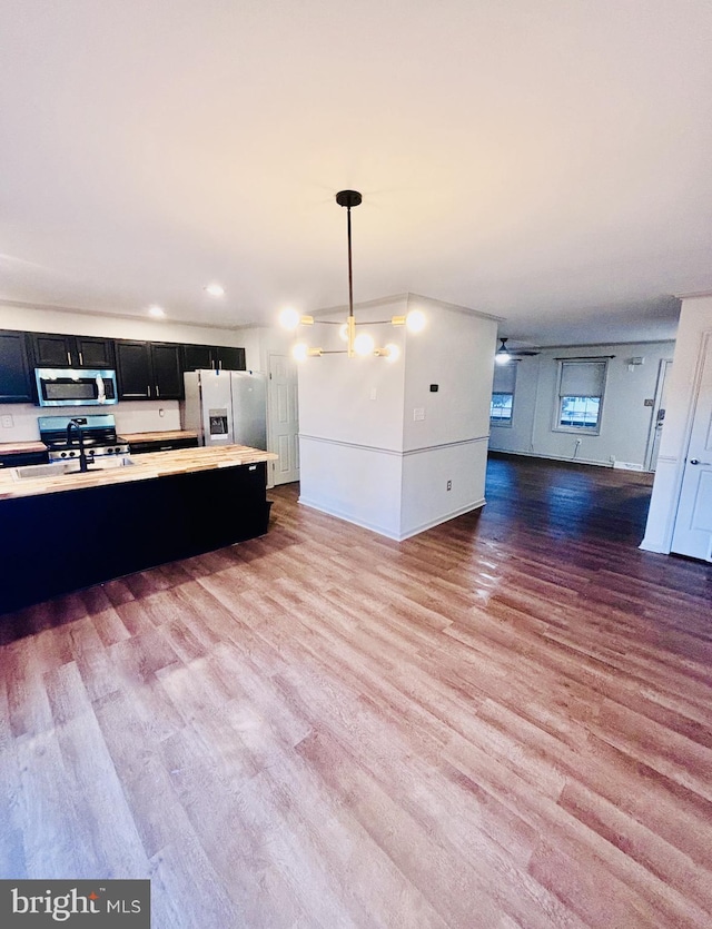 kitchen with sink, decorative light fixtures, stainless steel appliances, and light hardwood / wood-style floors