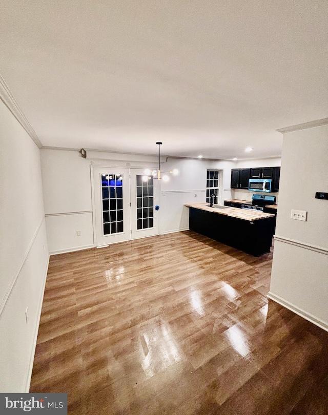 unfurnished living room with crown molding, sink, hardwood / wood-style flooring, and a notable chandelier