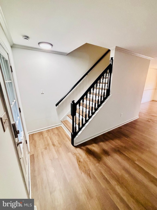 staircase with hardwood / wood-style floors and crown molding