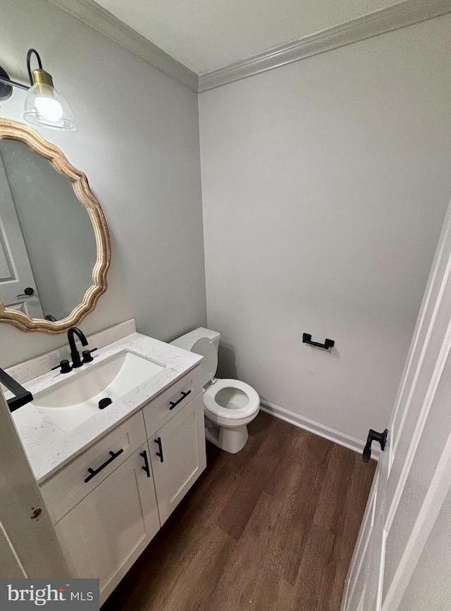 bathroom featuring ornamental molding, wood-type flooring, toilet, and vanity