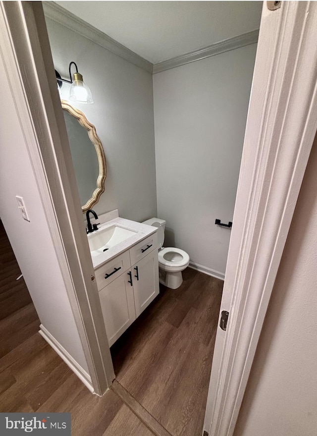 bathroom with vanity, wood-type flooring, ornamental molding, and toilet