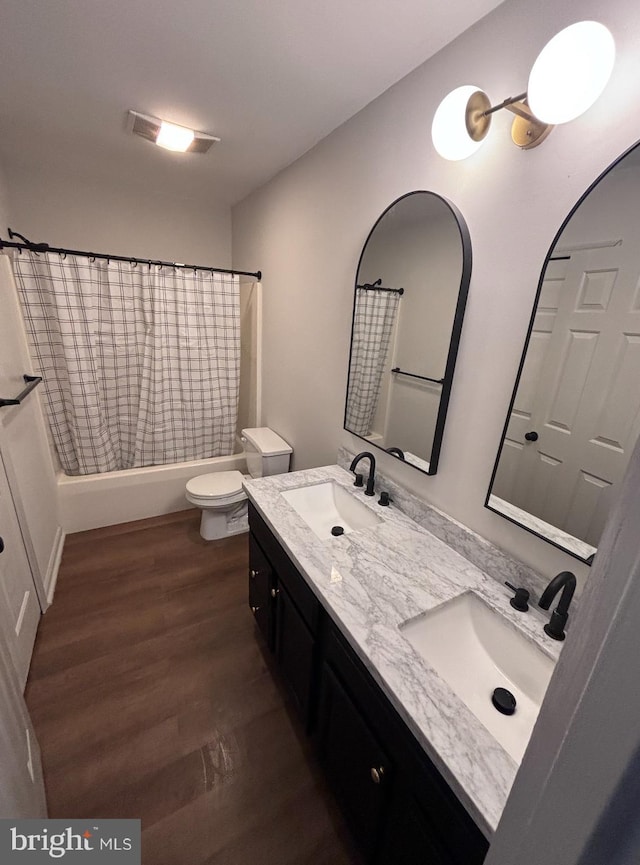 full bathroom featuring hardwood / wood-style flooring, vanity, shower / bathtub combination with curtain, and toilet