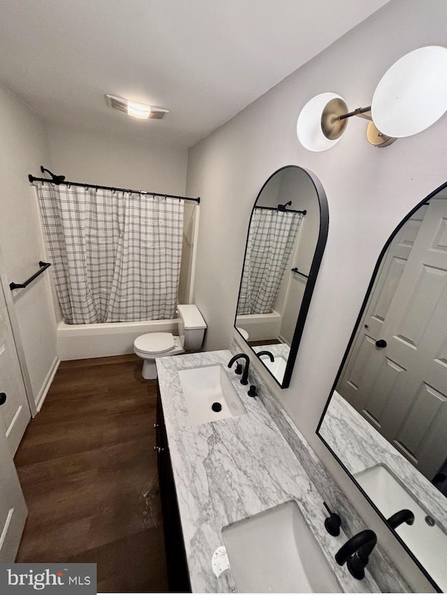 full bathroom featuring hardwood / wood-style flooring, vanity, toilet, and shower / tub combo