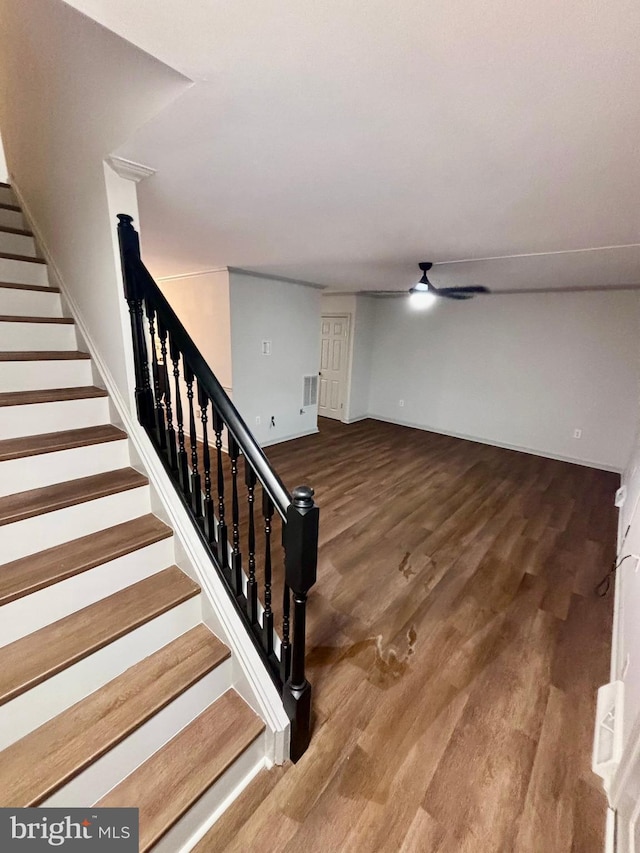 stairway with hardwood / wood-style floors and ceiling fan