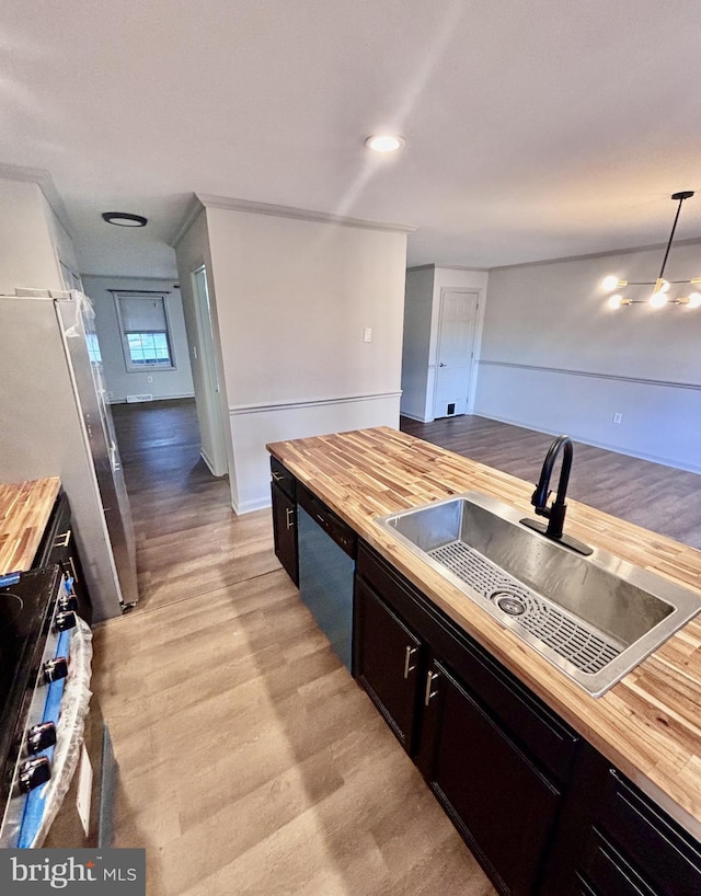 kitchen with wood counters, sink, pendant lighting, stainless steel appliances, and light hardwood / wood-style floors