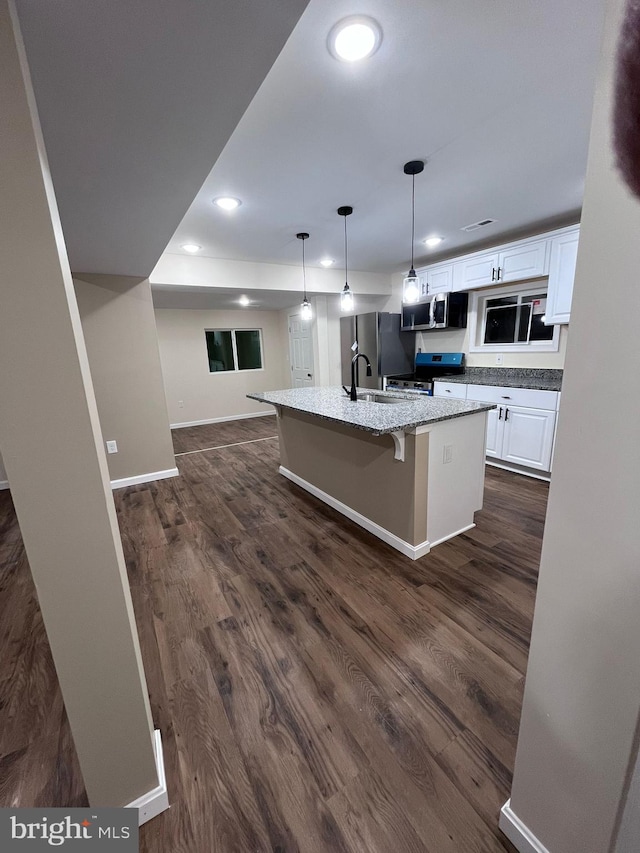 kitchen featuring dark hardwood / wood-style floors, white cabinetry, a breakfast bar area, hanging light fixtures, and stainless steel appliances