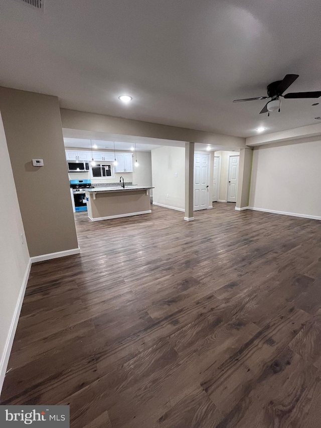 unfurnished living room with dark hardwood / wood-style floors, sink, and ceiling fan