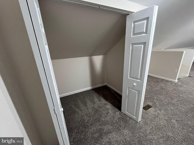 bonus room with vaulted ceiling and dark colored carpet