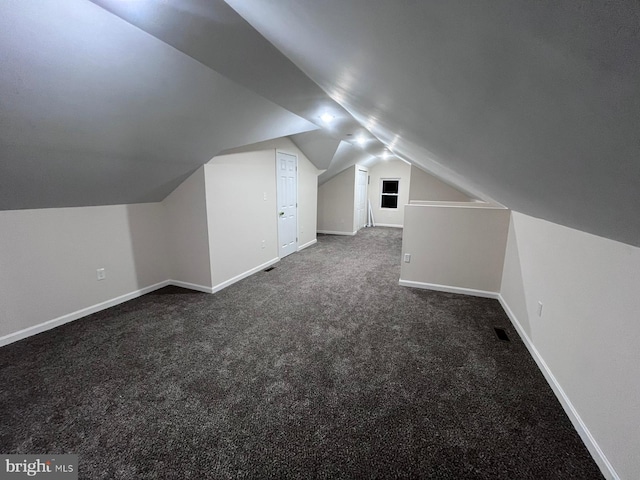 additional living space with dark colored carpet and lofted ceiling