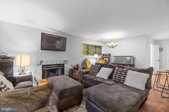 living area with a notable chandelier, a fireplace, and wood finished floors