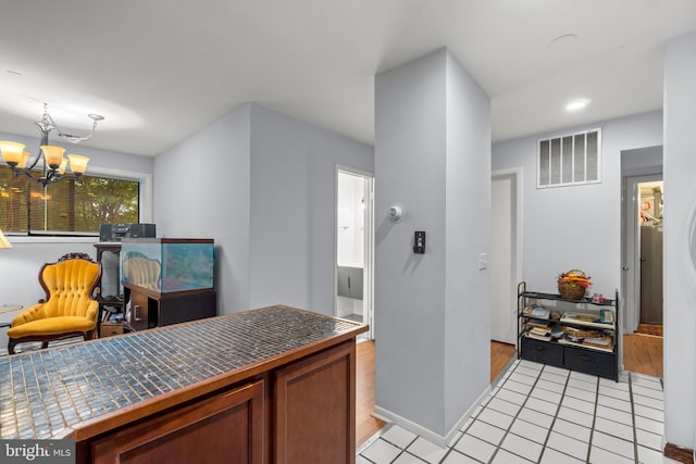 kitchen featuring tile countertops, an inviting chandelier, light tile patterned floors, and visible vents