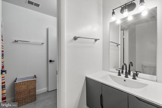 bathroom with toilet, vanity, and visible vents