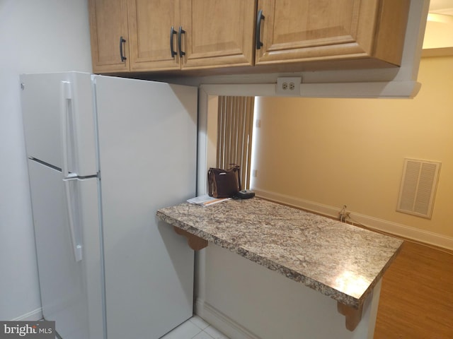 kitchen with baseboards, visible vents, freestanding refrigerator, light countertops, and light wood-type flooring