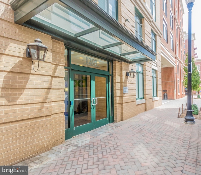 view of exterior entry featuring french doors and brick siding