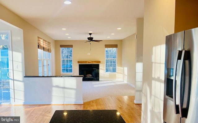 kitchen featuring light wood-type flooring, ceiling fan, dark stone counters, and stainless steel refrigerator with ice dispenser