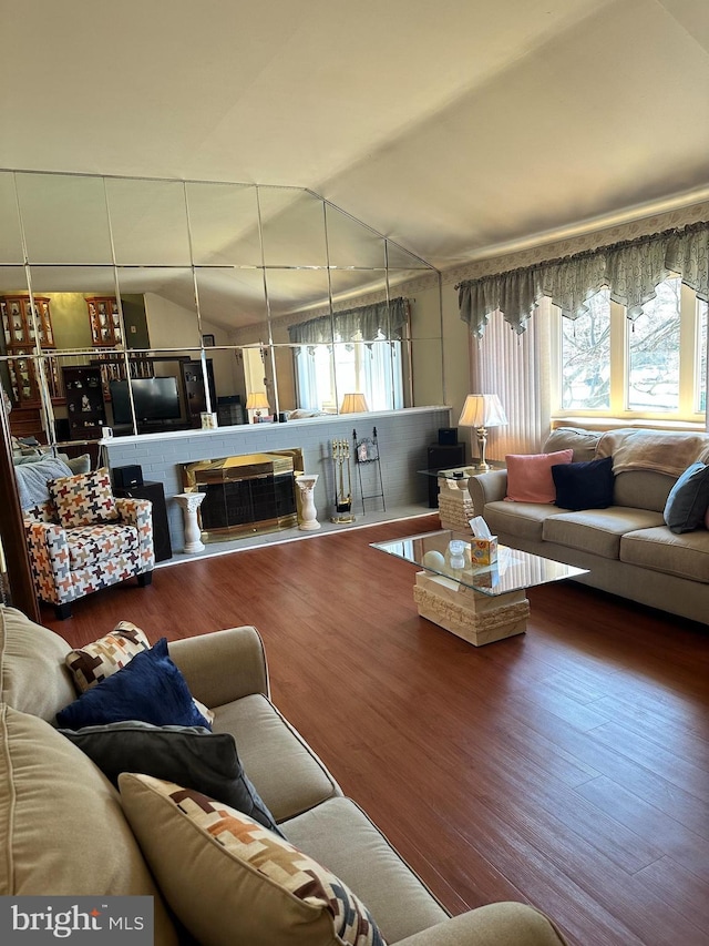 living room with lofted ceiling, a fireplace, and wood finished floors