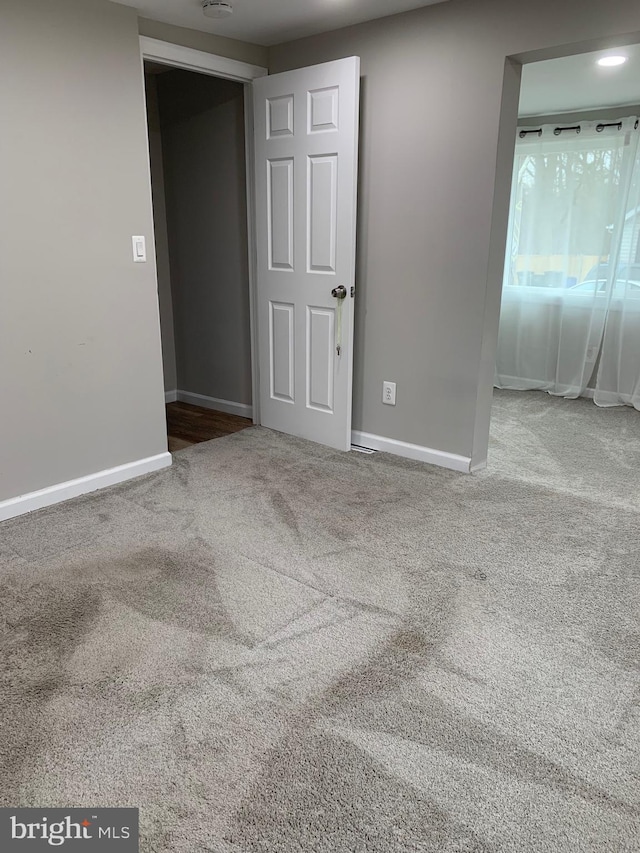 carpeted empty room featuring baseboards