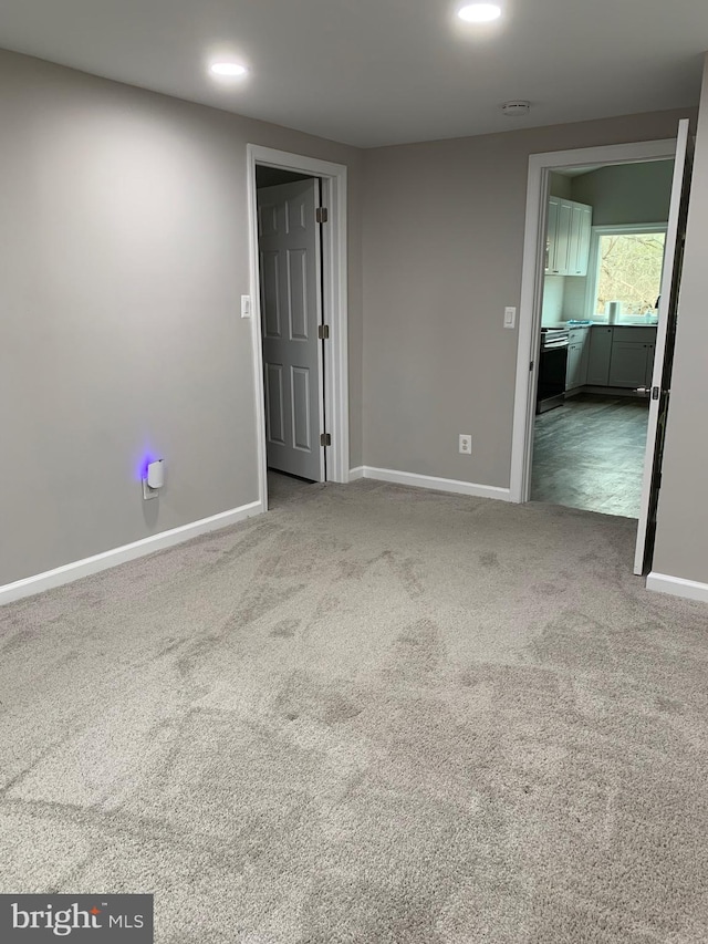 carpeted spare room featuring recessed lighting and baseboards