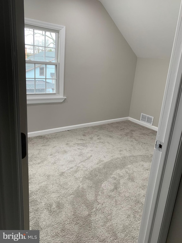 additional living space featuring baseboards, visible vents, vaulted ceiling, and carpet flooring