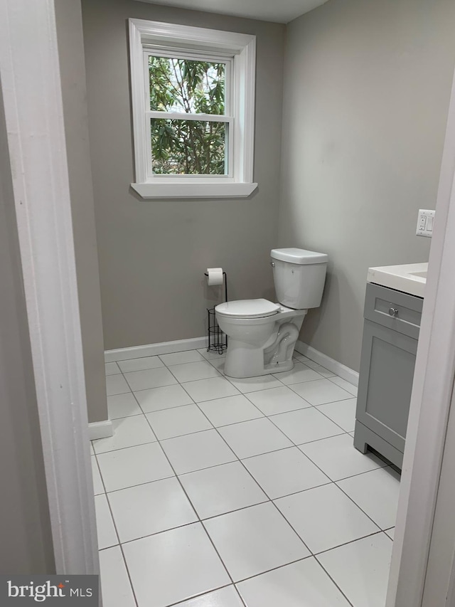 bathroom featuring toilet, tile patterned flooring, baseboards, and vanity