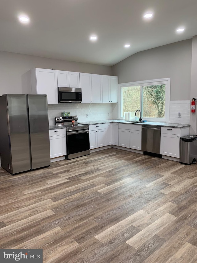 kitchen featuring stainless steel appliances, light wood finished floors, a sink, and white cabinets