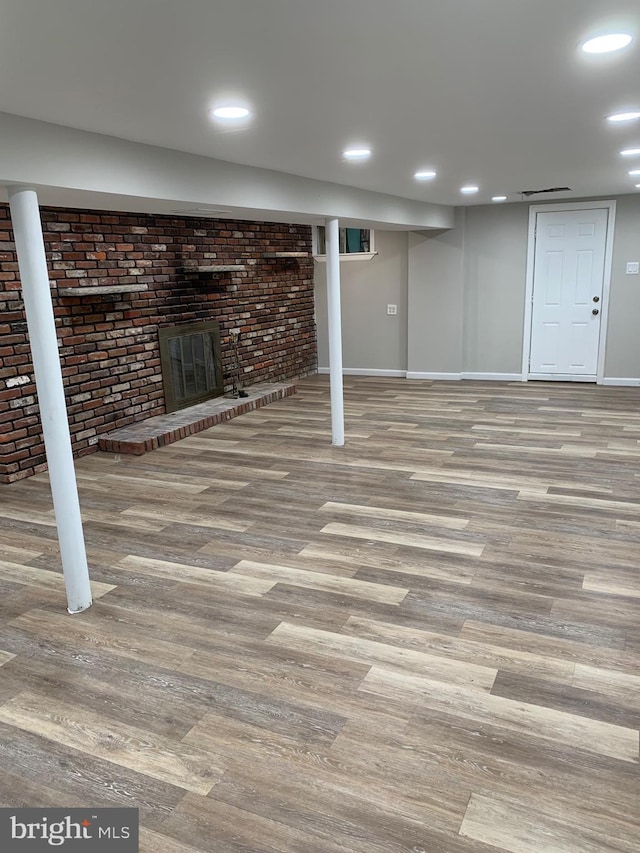 finished below grade area featuring a fireplace, wood finished floors, and recessed lighting