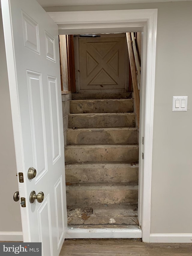 stairway featuring wood finished floors and baseboards