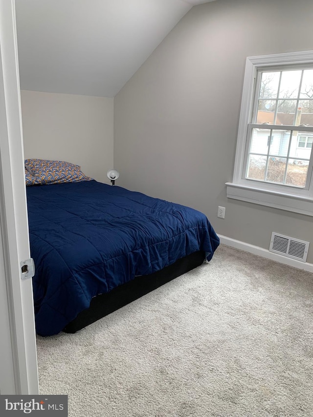 carpeted bedroom featuring lofted ceiling, baseboards, and visible vents